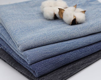 May include: A stack of different shades of blue denim fabric with a few cotton balls on top.