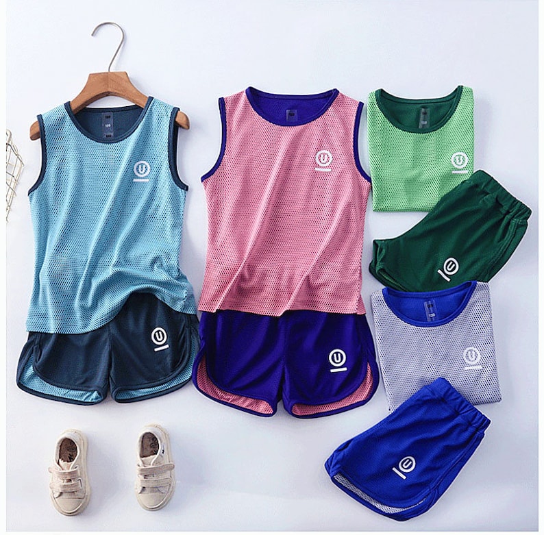 May include: A collection of athletic wear sets in various colors, including blue, pink, green, and gray. Each set features a sleeveless top and matching shorts. The tops and shorts have a mesh design and a white logo. The sets are displayed on a white surface.