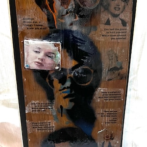 May include: A wooden panel with a collage of images and text. The panel features a black and white image of a person wearing sunglasses, a black and white image of a woman with blonde hair, and a black and white image of a woman with dark hair. The panel also includes text in white, black, and grey. The text includes the words "Goodbye, Norma Jeane" and "Though I never knew you at all".