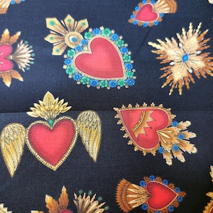 Könnte beinhalten: Ein schwarzer Stoff mit einem sich wiederholenden Muster aus roten, goldenen und blauen stilisierten Herzen mit Flügeln und verzierten Details.