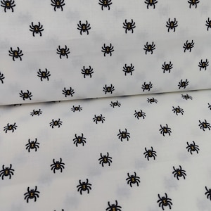 Könnte beinhalten: Weißer Stoff mit einem sich wiederholenden Muster aus schwarzen Spinnen. Die Spinnen haben ein kleines gelbes Detail in der Mitte.