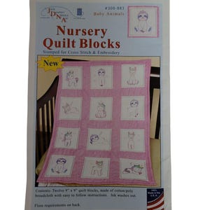Op de afbeelding: Een pakket "Nursery Quilt Blocks" voor kruissteek en borduren. De roze quilt heeft twaalf blokken van 23 cm x 23 cm met baby-dierontwerpen. Het pakket bevat instructies en is gemaakt in de VS.