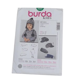 Puede incluir: Un sobre de patrón de costura Burda Kids 9507 para varias gorras. El frente muestra ilustraciones y una fotografía de gorros terminados, incluyendo estilos con orejeras y viseras. Las medidas de contorno de cabeza son 50cm, 52cm y 54cm.