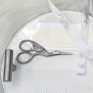 May include: A white ceramic tray with a silver metal tube and a pair of silver scissors with a bird design. The tray has the text "Et&uuml;az&uuml;l'&uuml;n Kahvesi" written on it. Two white satin ribbons with the text "Et&uuml;az&uuml;l" and "Kerim" are on the tray.