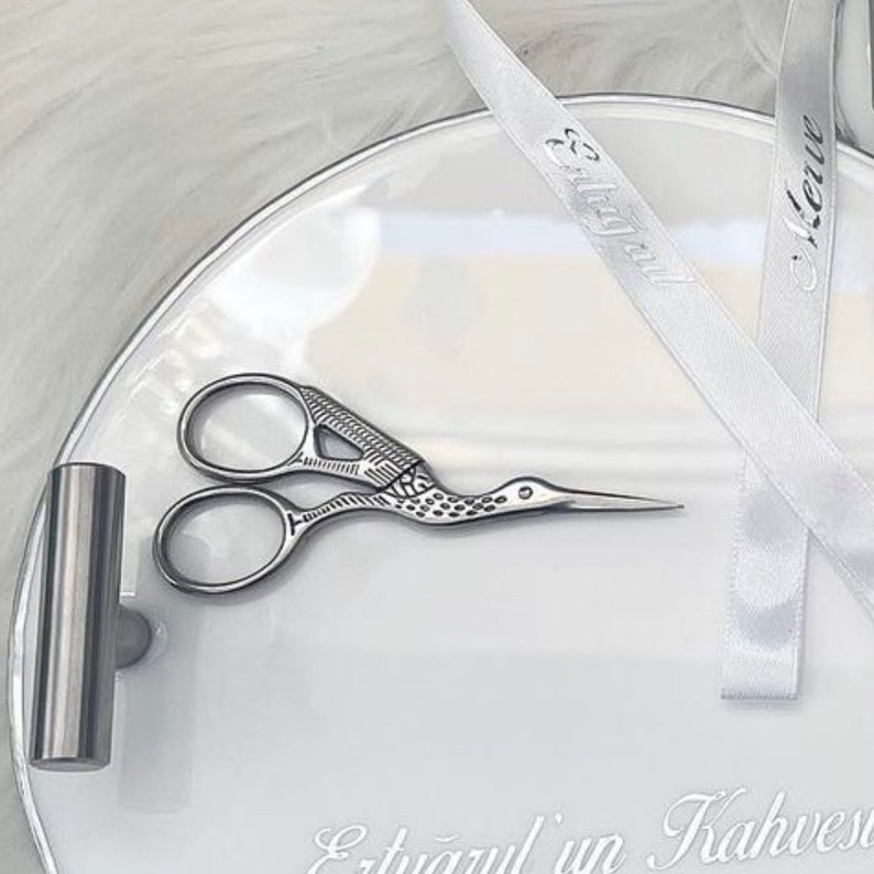 May include: A white ceramic tray with a silver metal tube and a pair of silver scissors with a bird design. The tray has the text "Et&uuml;az&uuml;l'&uuml;n Kahvesi" written on it. Two white satin ribbons with the text "Et&uuml;az&uuml;l" and "Kerim" are on the tray.