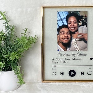 May include: Gold picture frame with a photo of two people, a mother and son, smiling. The frame has a music player design with the text "De Anna Joy Coleman", "A Song For Mama", "Boyz II Men", "0:15", and "5:03".