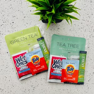 May include: Two sets of face mask packets, one green tea and one tea tree. Each set includes a face mask, two packets of wet wipes, two packets of Tide to Go wipes, and a single-serving packet of Trevi lemon lime drink.