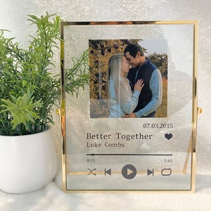May include: A gold-framed picture frame with a photo of a couple in a park. The frame has a music player design with the text "Better Together" and "Luke Combs" and the date "07.03.2015".