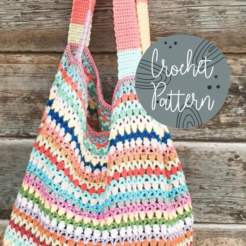 May include: A colorful crochet tote bag with a rainbow striped pattern. The bag has a wide, flat bottom and two long straps. The image includes the text "Crochet Pattern".