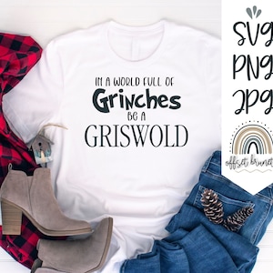 Puede incluir: Camiseta blanca con el texto negro "IN A WORLD FULL OF Grinches BE A GRISWOLD". La camiseta se combina con vaqueros azules, botas grises y una bufanda a cuadros rojos y negros. También hay un letrero decorativo con las palabras "SVG PNG JPG".