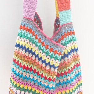 May include: A colorful crocheted tote bag with a rainbow striped pattern. The bag has two straps and is made with a variety of different colored yarns.
