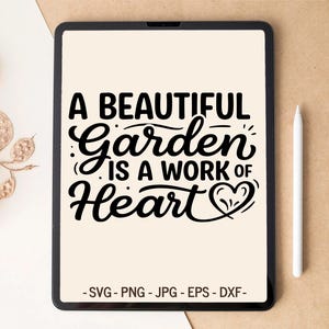 以下が含まれることがあります： 黒い文字で「A BEAUTIFUL Garden IS A WORK OF Heart」と書かれ、ハートのアイコンが表示されたデジタルタブレット。テキストの下にはSVG、PNG、JPG、EPS、DXFのファイル形式が記載されている。タブレットの右側には白いスタイラスペンが置かれている。