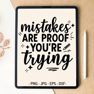 Könnte beinhalten: Ein digitales Tablet mit dem schwarzen Text "mistakes ARE PROOF YOU'RE TRYING" auf cremefarbenem Hintergrund, ergänzt durch kleine Stern- und Bleistiftsymbole. Unter dem Text sind die Dateiformate "PNG - JPG - EPS - DXF" deutlich zu sehen.