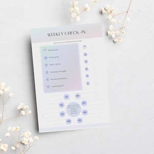 May include: A weekly check-in sheet with a gradient background and the text "WEEKLY CHECK-IN:". It includes sections to rate feelings with emoticons and prompts for reflection. The sheet is surrounded by white flowers.