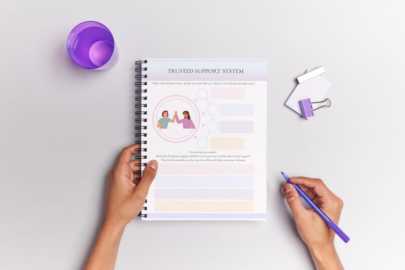 May include: A spiral bound notebook with a purple and white cover. The cover has the text "Trusted Support System" and an illustration of two people giving each other a high five. The notebook is open to a page with a chart for listing names and how they support you.