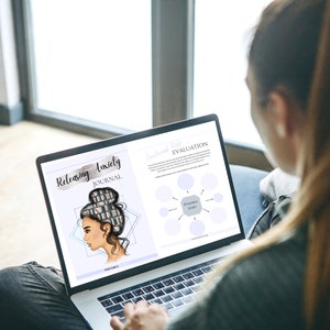 May include: A person using a laptop computer to view a digital journal titled "Releasing Anxiety Journal". The journal cover features a woman with a bun and a stack of books in her hair. The laptop screen also shows a "Personal Wish Evaluation" page with a diagram.