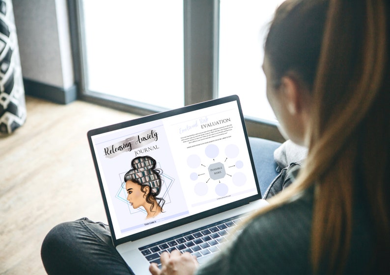 May include: A person using a laptop computer to view a digital journal titled "Releasing Anxiety Journal". The journal cover features a woman with a bun and a stack of books in her hair. The laptop screen also shows a "Personal Wish Evaluation" page with a diagram.