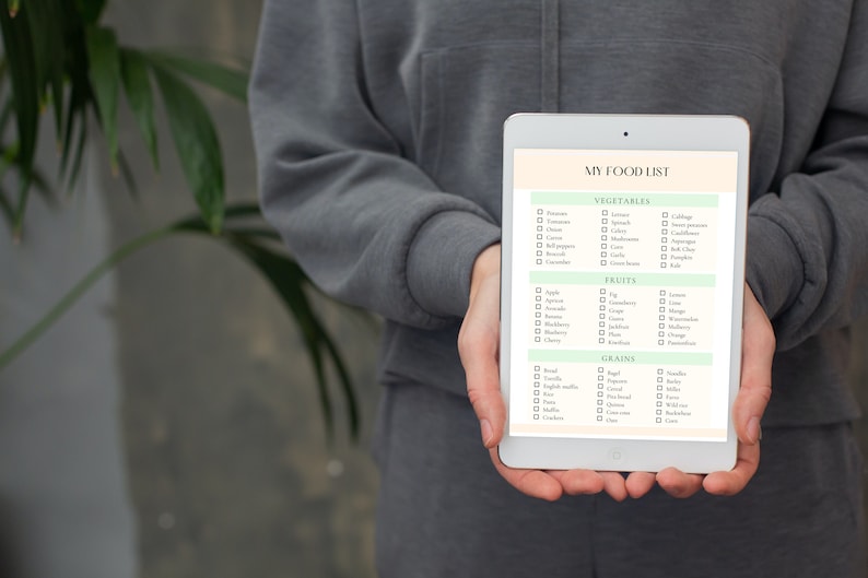 May include: A digital tablet with a white background and green accents displays a checklist titled "My Food List" with categories for vegetables, fruits, and grains. Each category has a list of common food items with checkboxes next to them.