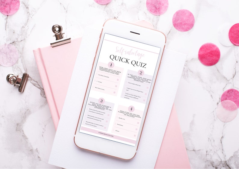 Op de afbeelding: Een witte smartphone waarop een roze en witte snelle zelfsabotagequiz met vier vragen te zien is. De telefoon ligt op een wit oppervlak met een roze notitieboekje en roze confetti.