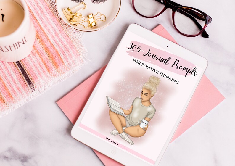 Puede incluir: Una tableta digital que muestra un gr&aacute;fico rosa y blanco de una mujer leyendo un libro y sosteniendo una taza. El texto en la tableta dice "365 Journal Prompts for Positive Thinking" y "This Girl's".