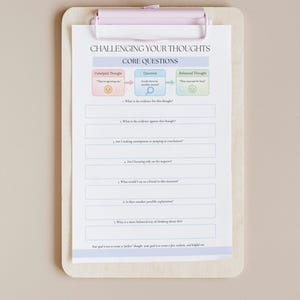 May include: A clipboard with a pink clip holds a worksheet titled "Challenging Your Thoughts." The worksheet has sections for "Unhelpful Thought," "Question," and "Balanced Thought," with prompts to analyze and reframe thinking patterns.