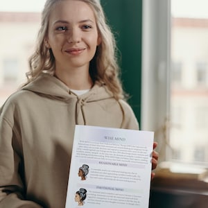 May include: A woman in a beige hoodie holds a white paper with text and illustrations. The paper's title is "WISE MIND" and describes concepts of emotional and rational thinking. The illustrations depict women with different hairstyles.