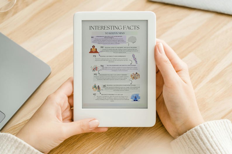 May include: A white e-reader showing a page titled "Interesting Facts To Keep In Mind." The page has colourful illustrations and text. The e-reader is held by a person, with a laptop visible in the background on a wooden surface.