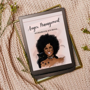 Op de afbeelding: Een zwart-wit digitaal e-boek met de titel "Anger Management Workbook Journal" op een roze achtergrond met een zwarte kat en een vrouw met een afrokapsel.