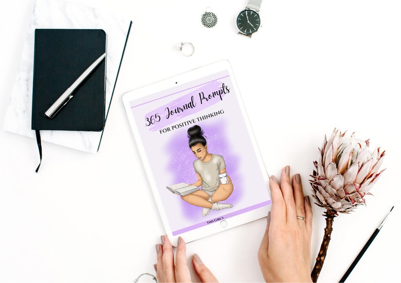Puede incluir: Una tableta digital que muestra una portada p&uacute;rpura y blanca con el texto "365 Journal Prompts for Positive Thinking". La portada presenta una ilustraci&oacute;n de una persona sentada con un libro y una taza.