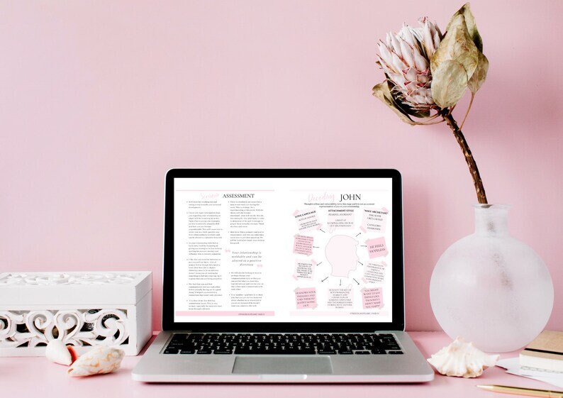 May include: A laptop computer open to a document with the title "Brain Dump JOHN" and a diagram with text bubbles. The laptop is on a pink surface with a white box, seashells, and a vase with a dried flower.