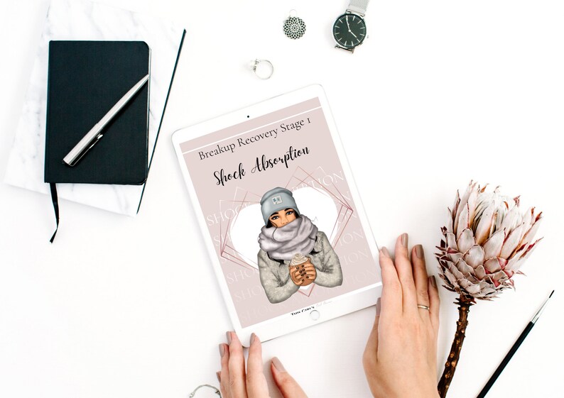 May include: A digital tablet displaying a pink and white graphic with the text "Breakup Recovery Stage 1: Shock Absorption". The graphic features a woman wearing a gray hat, scarf, and jacket, holding a cup of coffee.