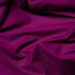 May include: A close-up of a deep purple fabric with soft folds and wrinkles. The fabric has a smooth, silky texture.
