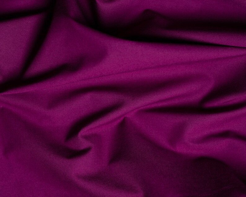 May include: A close-up of a deep purple fabric with soft folds and wrinkles. The fabric has a smooth, silky texture.