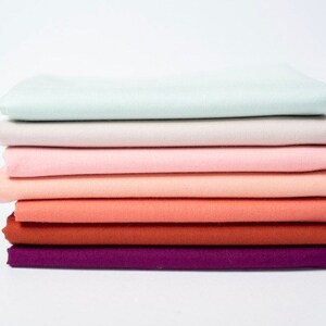 May include: Stack of eight fabric squares in a gradient of colors, starting with a light blue and transitioning to a deep purple.