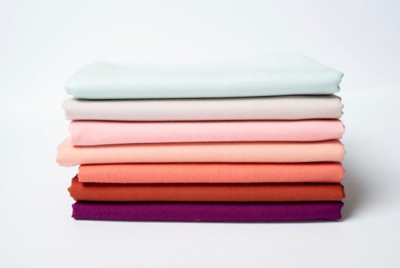 May include: Stack of eight fabric squares in a gradient of colors, starting with a light blue and transitioning to a deep purple.