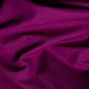 May include: A close-up of a deep purple fabric with soft folds and wrinkles. The fabric has a smooth, even texture.