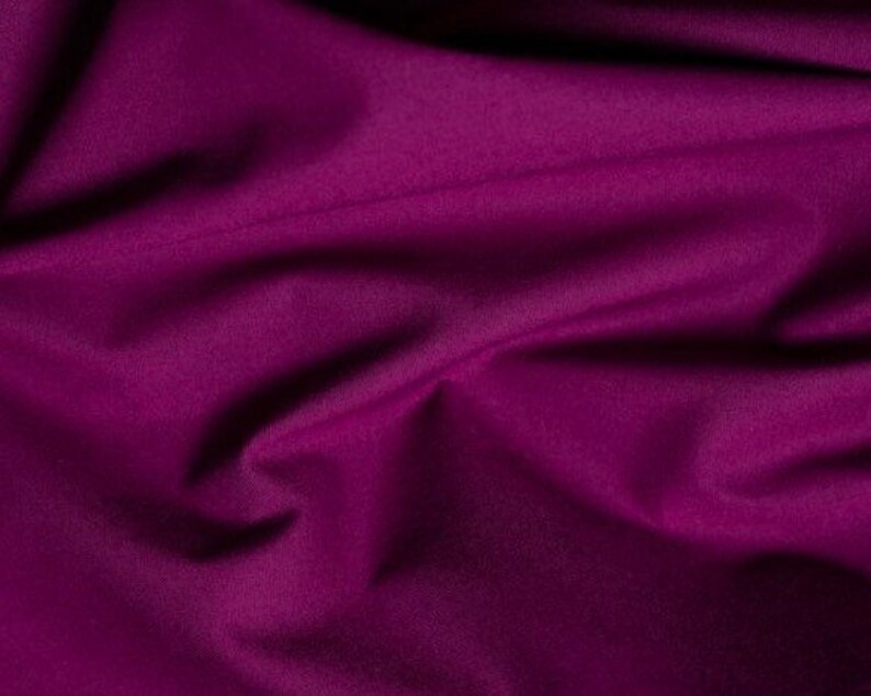 May include: A close-up of a deep purple fabric with soft folds and wrinkles. The fabric has a smooth, even texture.