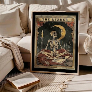 May include: A framed art print depicting a skeleton meditating beneath a crescent moon and starry sky. The artwork includes a lit candle, books, and the text "THE READER". The colour scheme features gold, red, and black.
