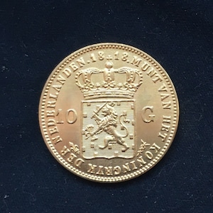 May include: A gold coin featuring a lion and a crown. The coin inscription reads "KONING DER NEDERLANDEN 1818 MUNT VAN", which translates to "King of the Netherlands 1818 Mint of".