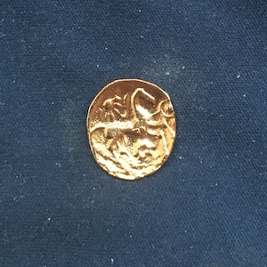 May include: A gold coin featuring a design of a horse and rider on one side.