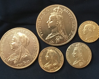 May include: Five gold coins featuring Queen Victoria's profile. The coins are in various sizes and have different inscriptions, including "VICTORIA DEI GRA BRIT REGINA" and "VICTORIA D.G. BRITT. REG. F.D."