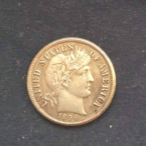 Könnte beinhalten: Eine silberne US-Dime-Münze mit den Worten "United States of America" und dem Jahr "1896" darauf. Die Münze zeigt ein Porträt von Liberty mit einem Kranz auf dem Kopf.