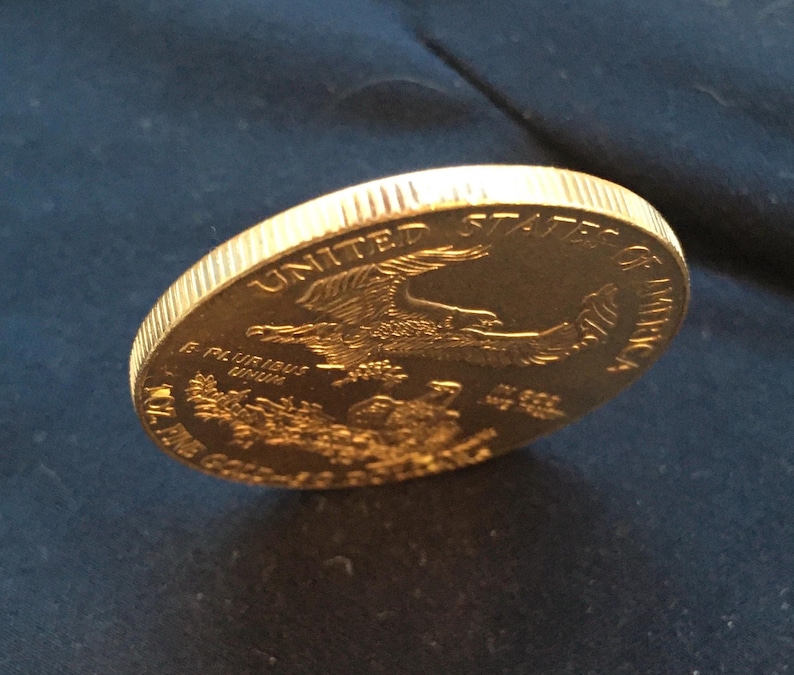 May include: A gold-colored United States of America coin with an eagle design and the words "E Pluribus Unum" and "In God We Trust".