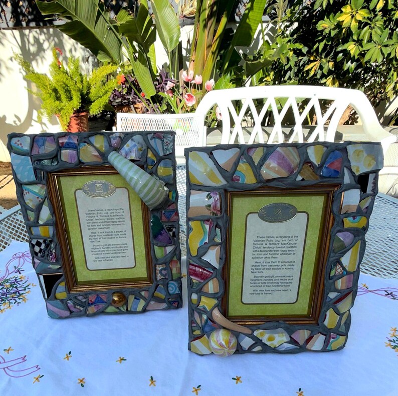 Puede incluir: Dos marcos de fotos rectangulares con un borde de mosaico hecho de fragmentos de cer&aacute;mica de colores incrustados en lechada gris. Cada marco incluye un borde interior dorado y una tarjeta impresa con texto descriptivo.