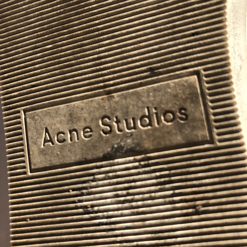 May include: Close-up of the sole of a shoe with the text "Acne Studios" embossed on it.