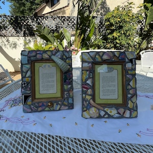 Puede incluir: Dos marcos de fotos rectangulares con un borde de mosaico hecho de fragmentos de cer&aacute;mica multicolor sobre lechada gris. Cada marco incluye una inserci&oacute;n de color verde claro con texto impreso y detalles decorativos de cer&aacute;mica.