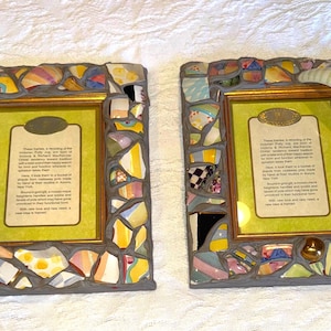 Puede incluir: Dos marcos de fotos rectangulares con un borde de mosaico hecho de fragmentos de cer&aacute;mica de colores fijados en lechada gris. Cada marco contiene una inserci&oacute;n de color verde claro con texto impreso y un borde interior dorado.