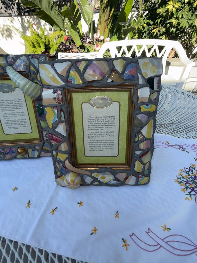 Puede incluir: Un marco de fotos rectangular con un borde de mosaico hecho de fragmentos de cer&aacute;mica coloridos fijados en lechada gris. El marco incluye un borde interior dorado y una inserci&oacute;n central con texto impreso sobre el reciclaje de jarras.
