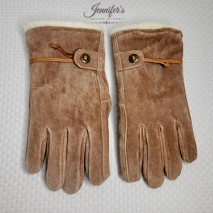 May include: A pair of brown suede gloves with a fleece lining. The gloves have a strap with a button closure at the wrist.