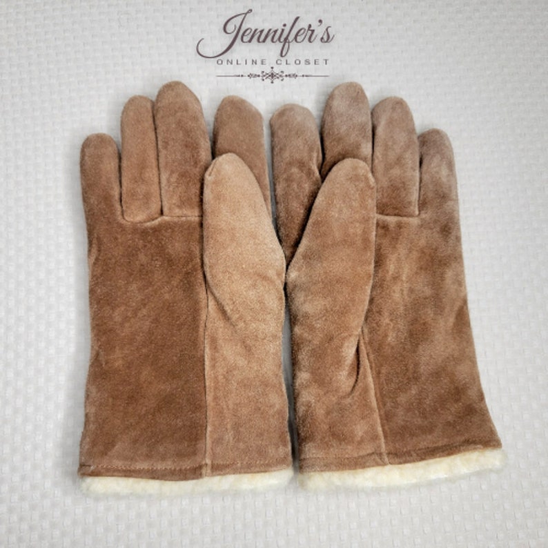 May include: A pair of brown suede gloves with a white fleece lining. The gloves are lined with a soft, warm fleece material.